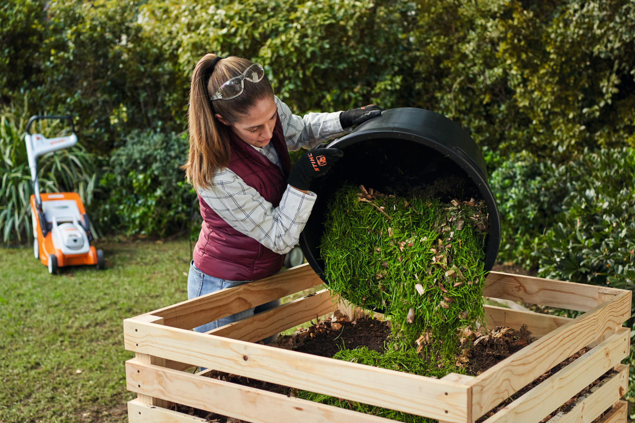 A man wearing ear protection using a STIHL GHE 140 electric shredder in a garden