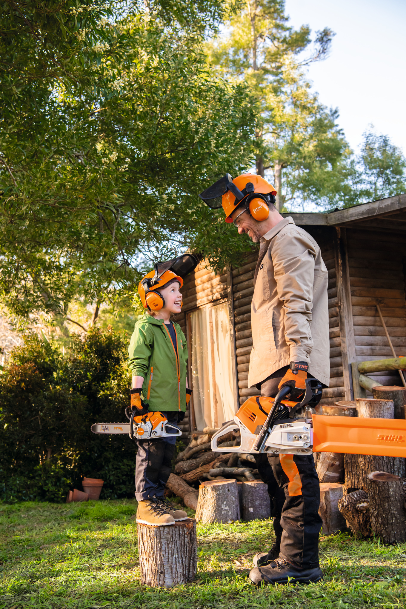 Father and daughter holding chainsaws and smiling at eachother