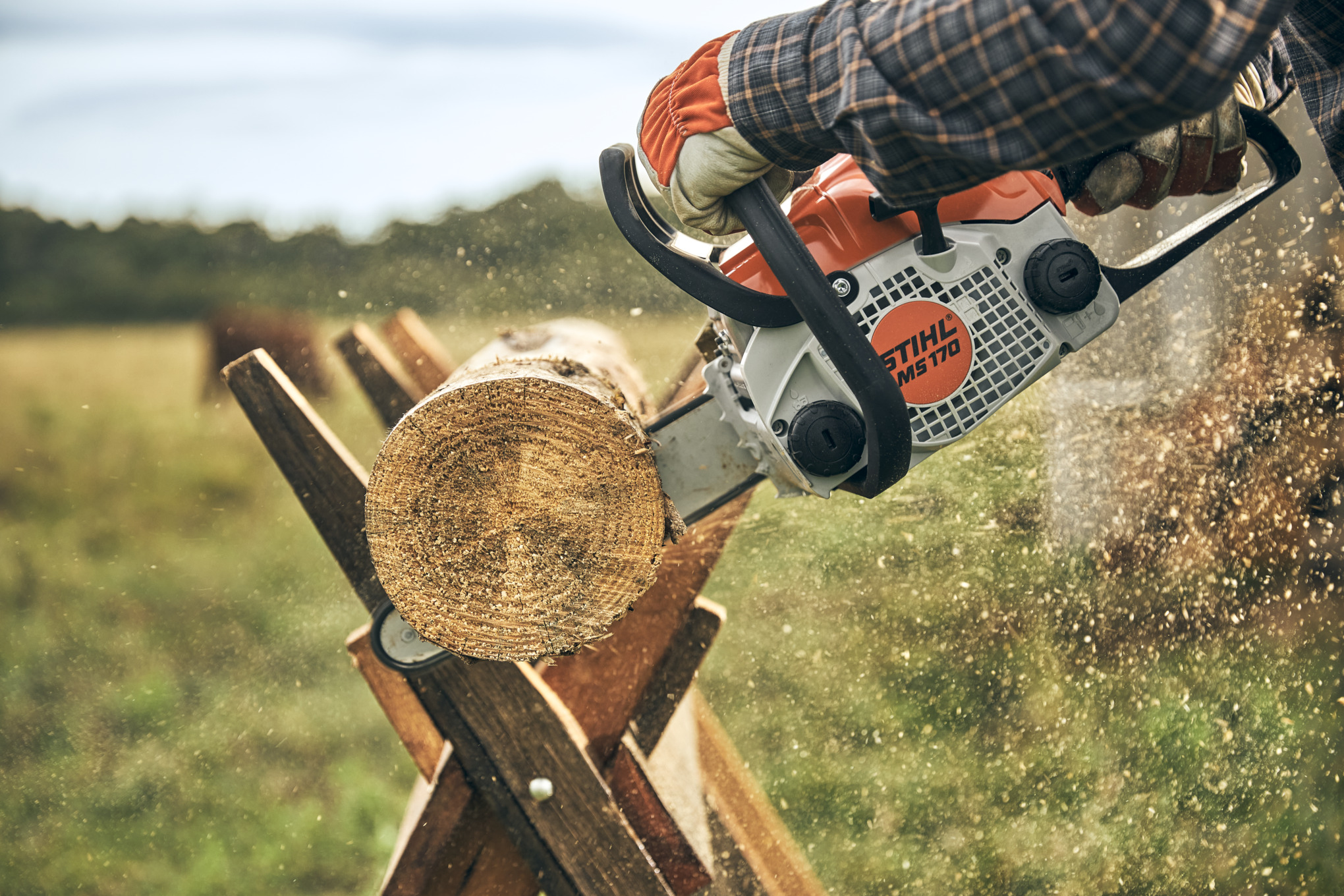 Chainsaw cutting log on sawhorse