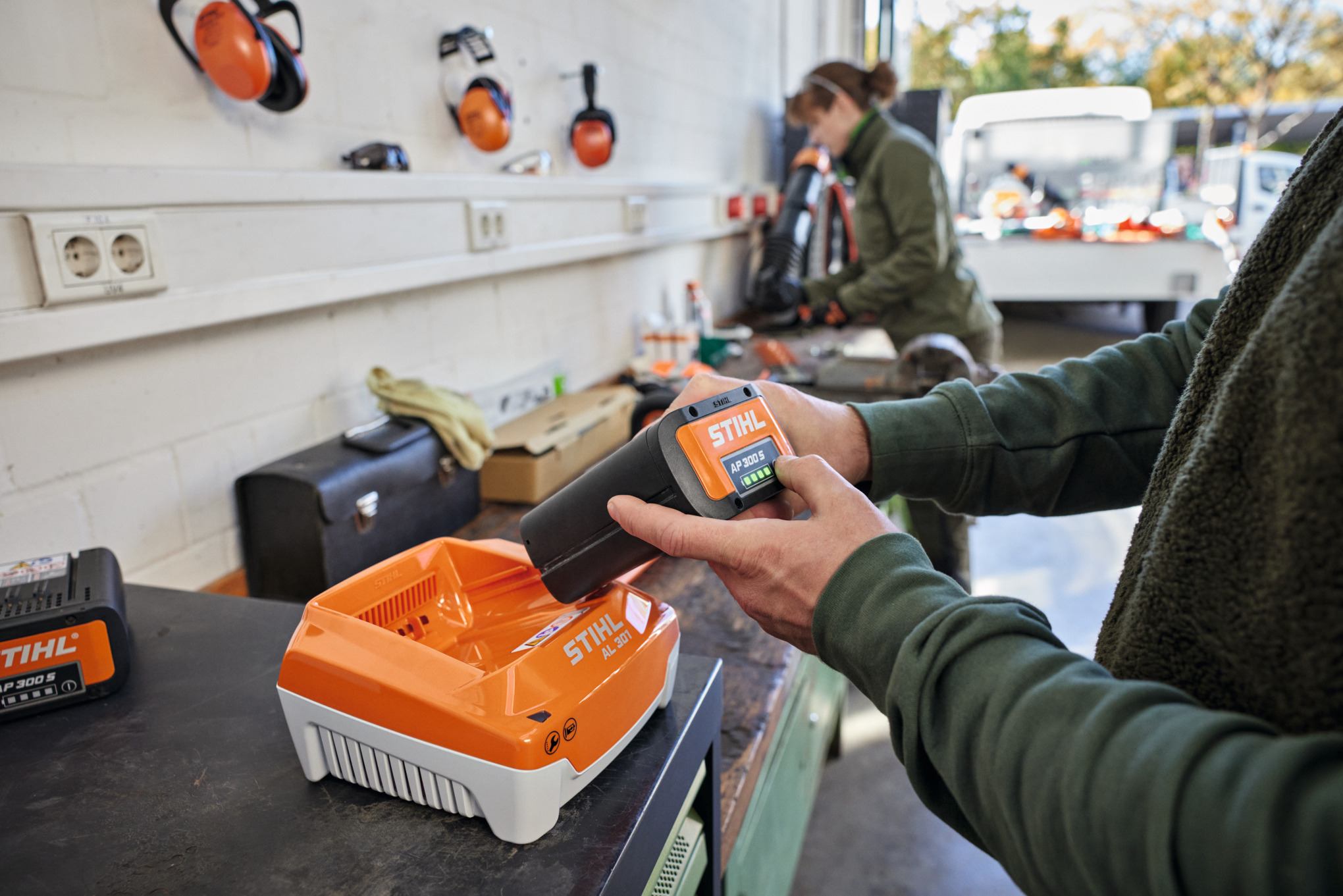 One person inserts a STIHL AP 300 S battery into a STIHL AL 301 quick charger