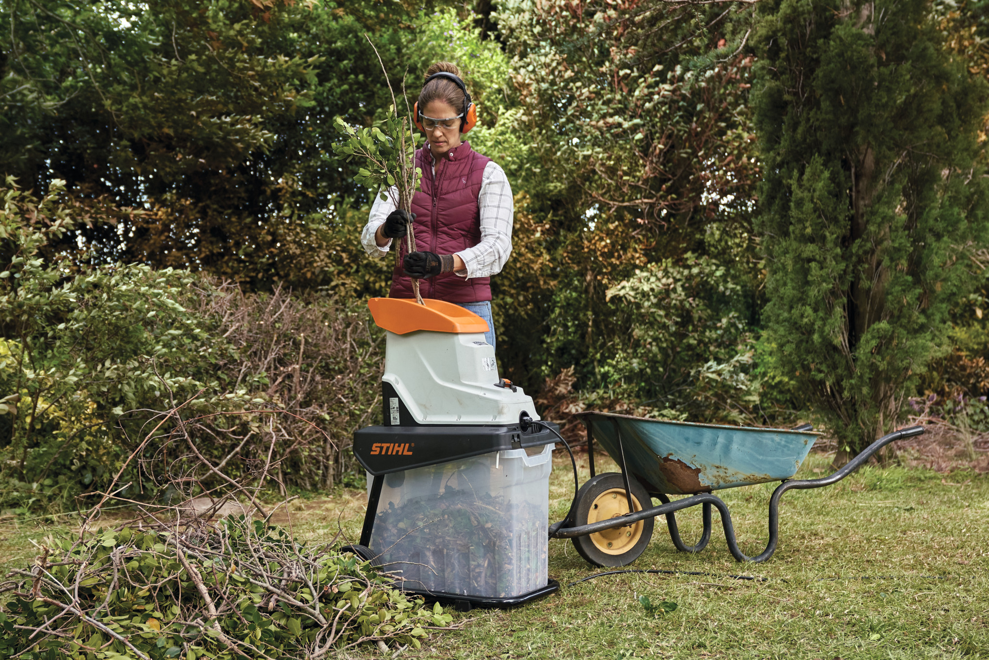Woman feeding branches through shredder