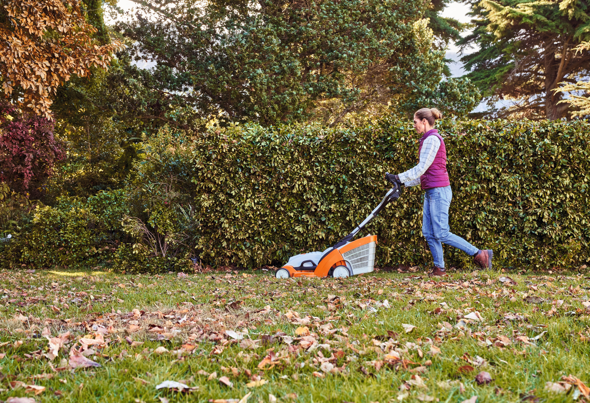 a woman lawns her garden with a STIHL lawn mower