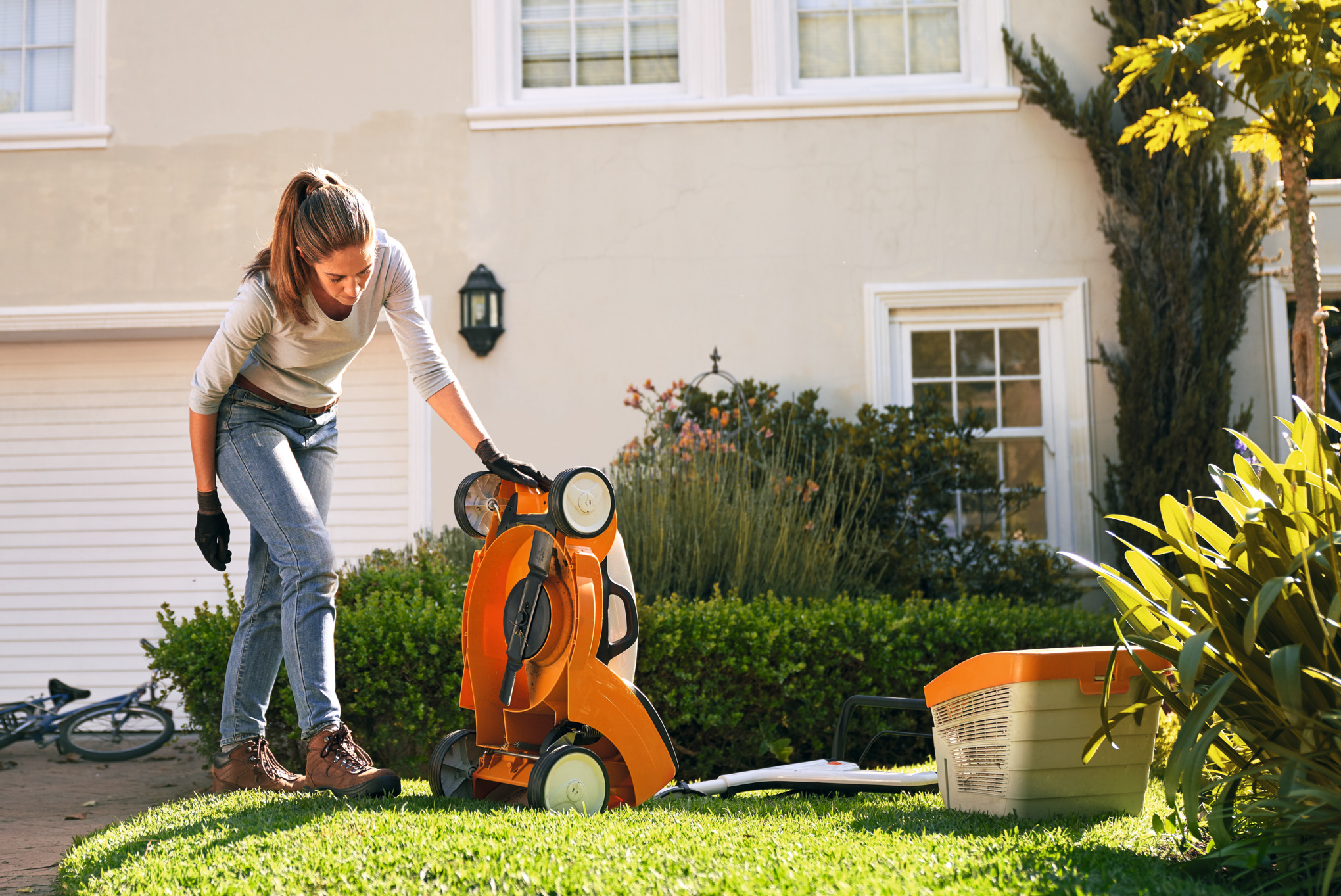Woman inspecting undercarriage of lawn mower