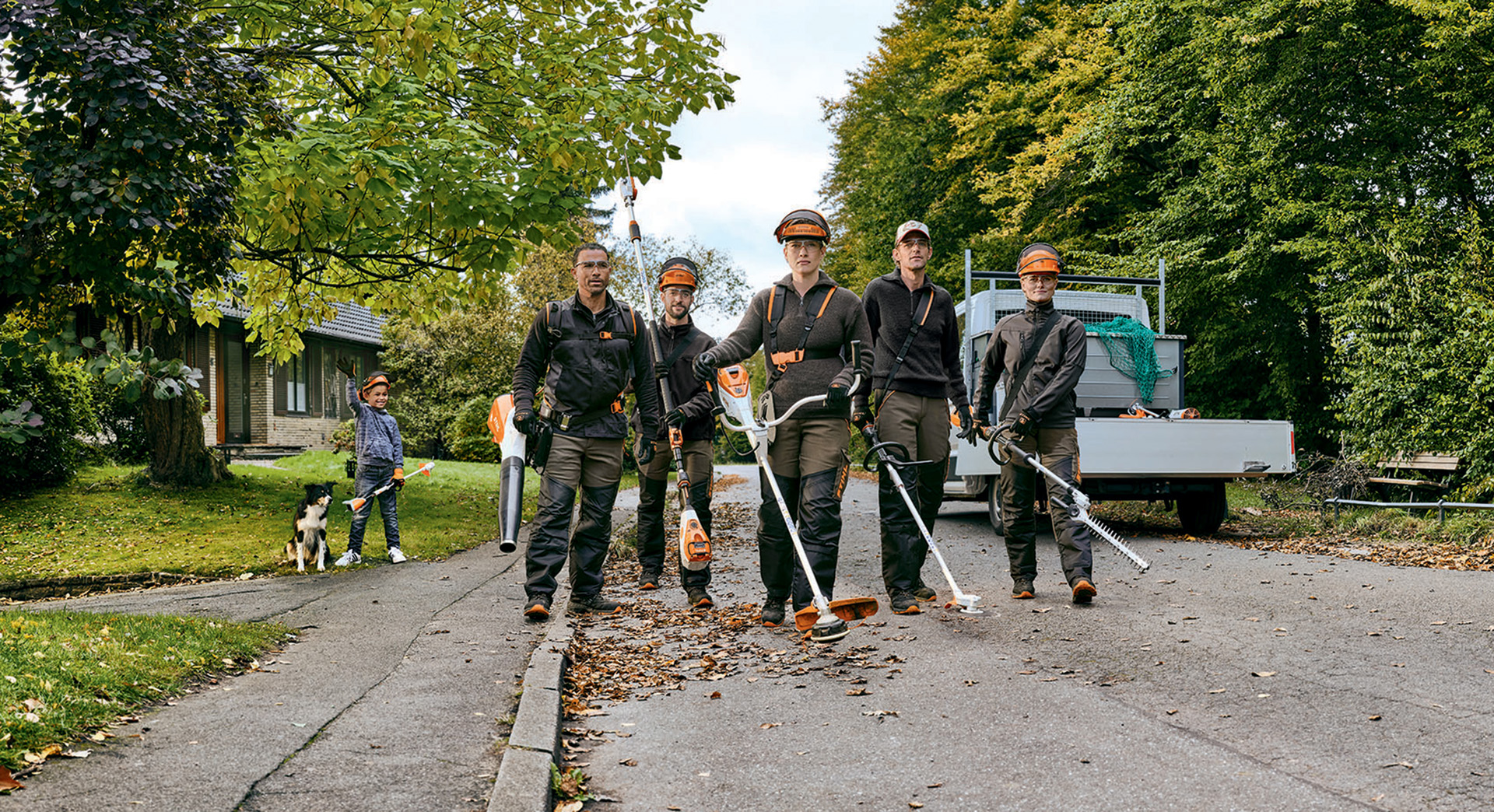 A gardening and landscaping team with STIHL professional battery power tools walking along a street.