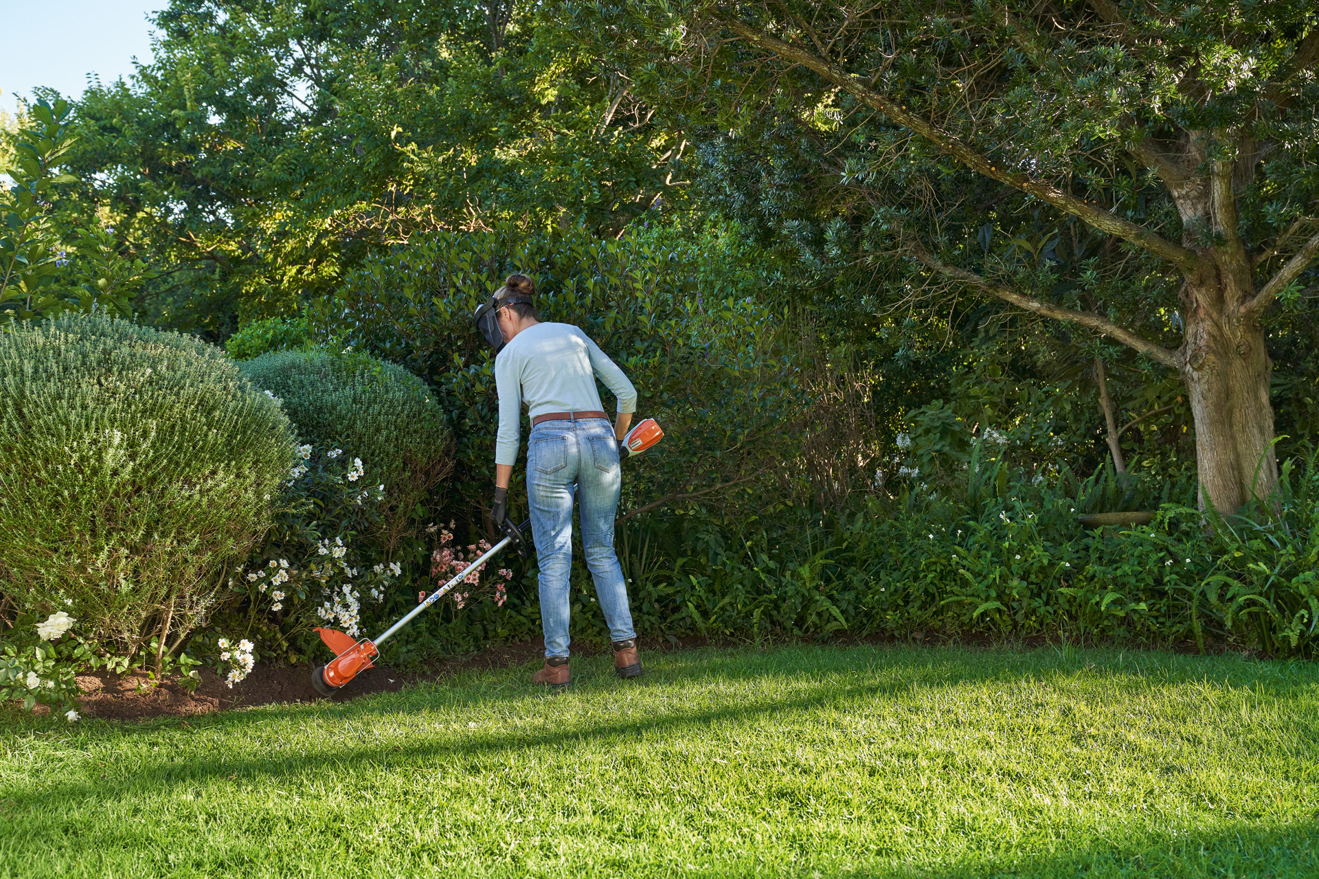 Woman using a STIHL FSA 60 cordless brushcutter to maintain English-style lawn edging 