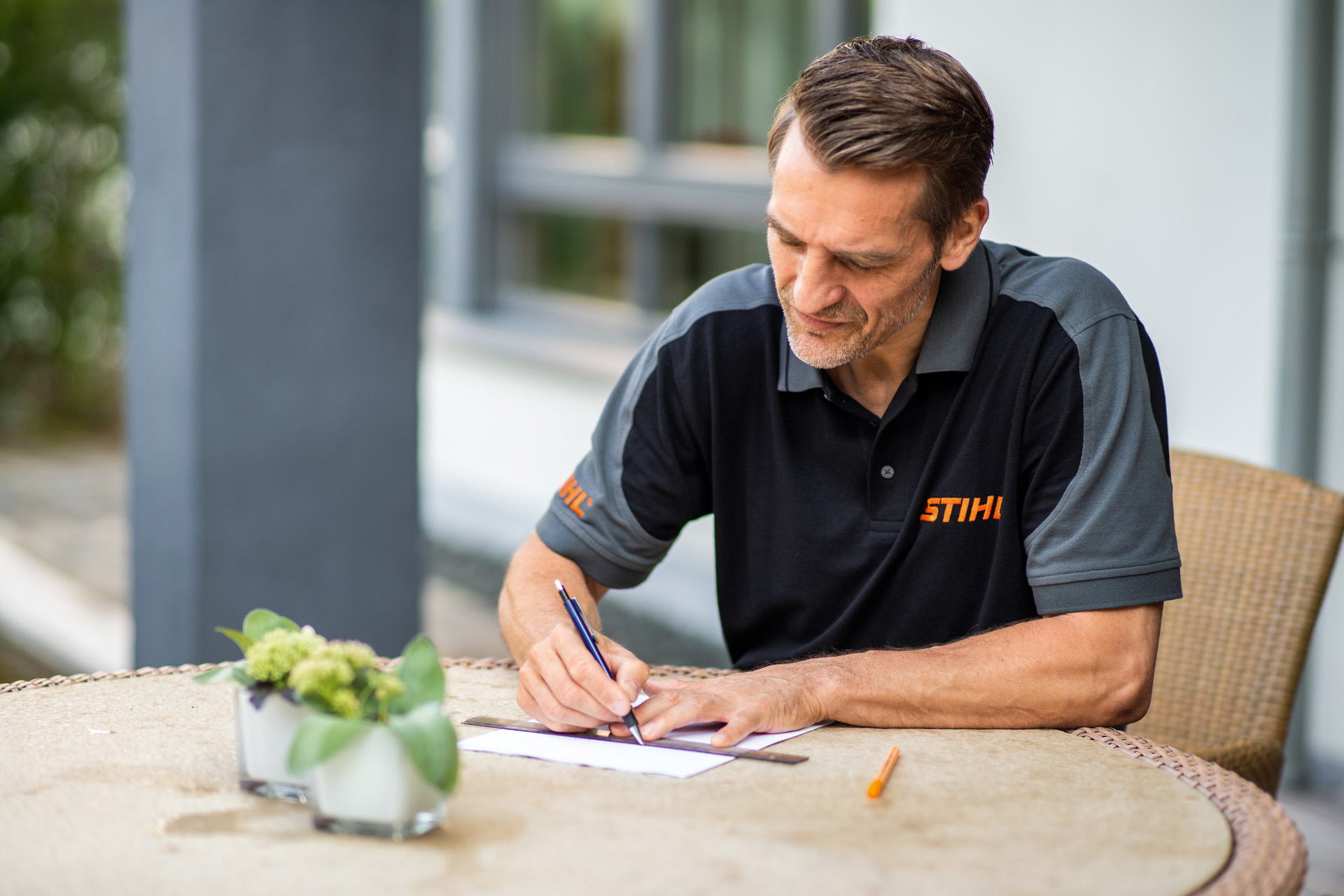 STIHL dealer sitting at the garden table and putting together a plan for the lawn area to be mown by the iMOW robotic mower