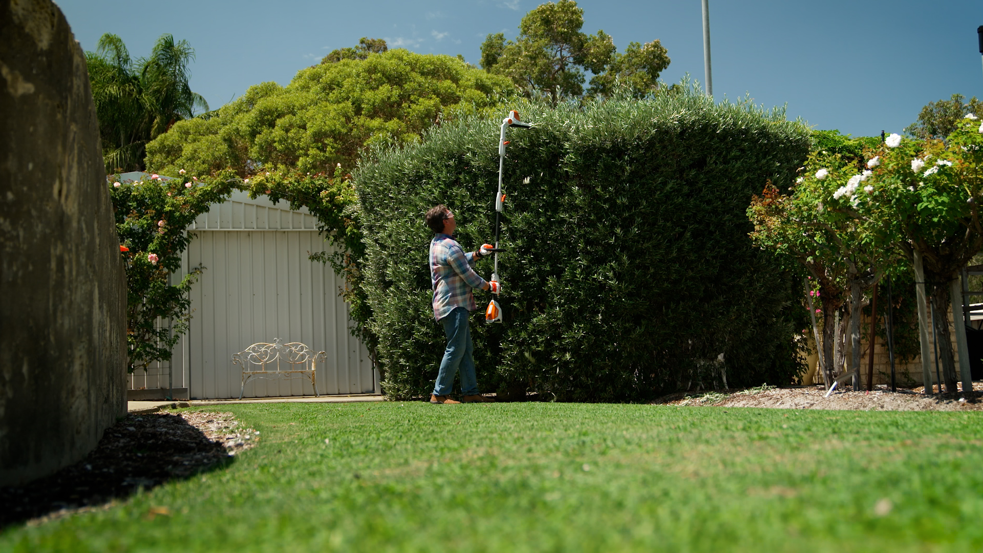 a man is trimming hedge in a big garden