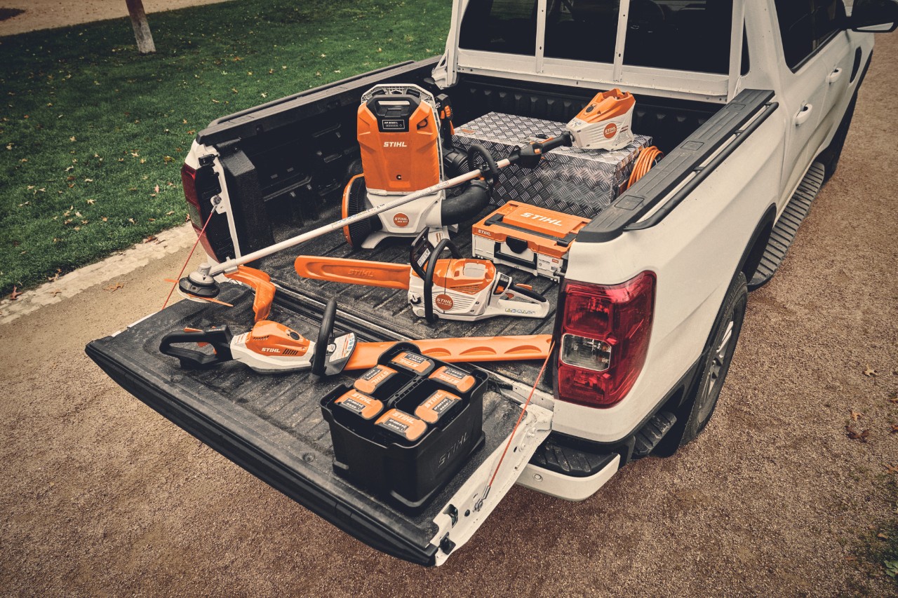 Various battery-powered devices from the STIHL AP system and the matching batteries on the loading area of a vehicle