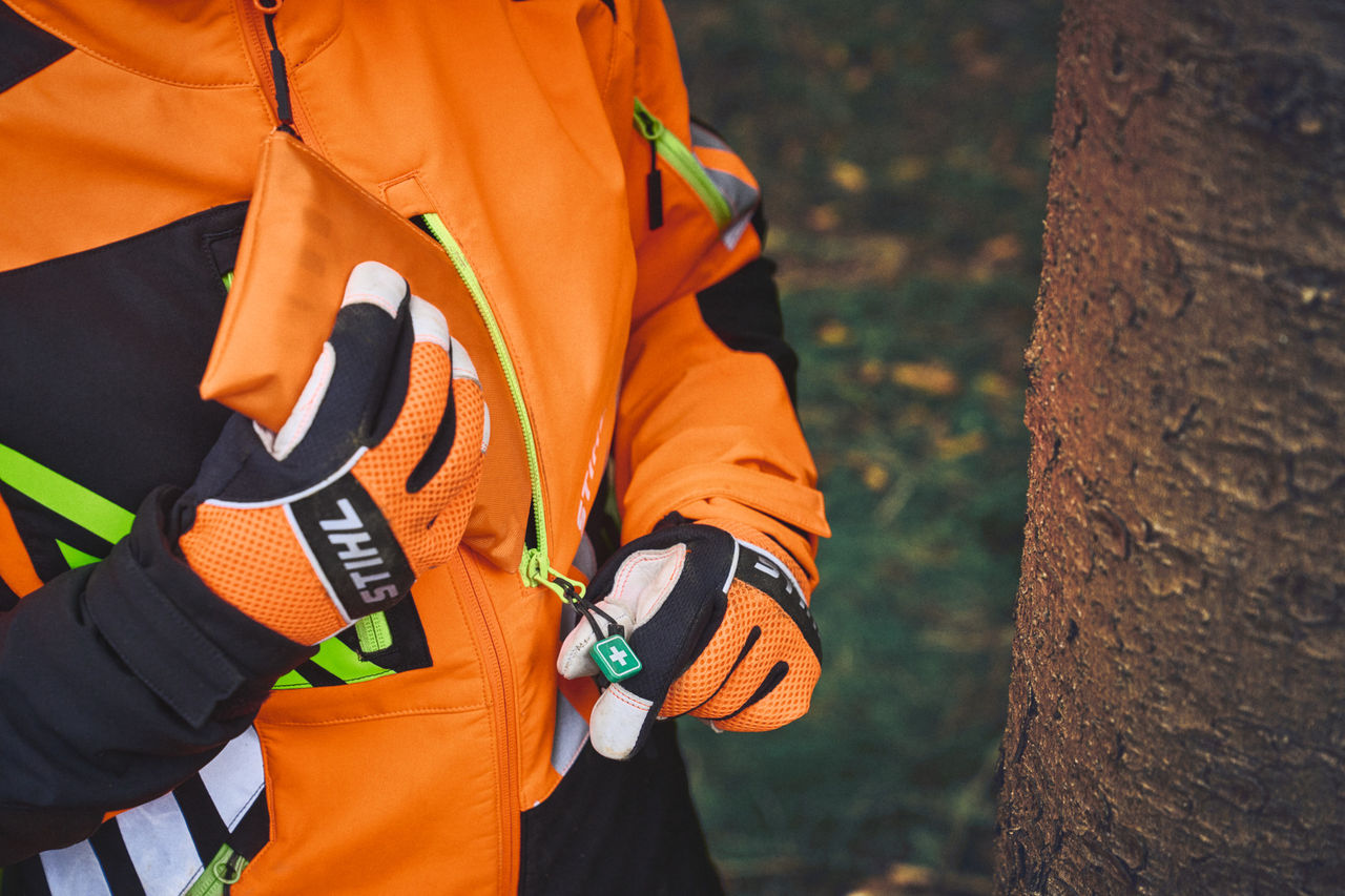 Close-up of a person in STIHL ADVANCE FlexTEC with ShellTEC first aid zipper pendant in the forest