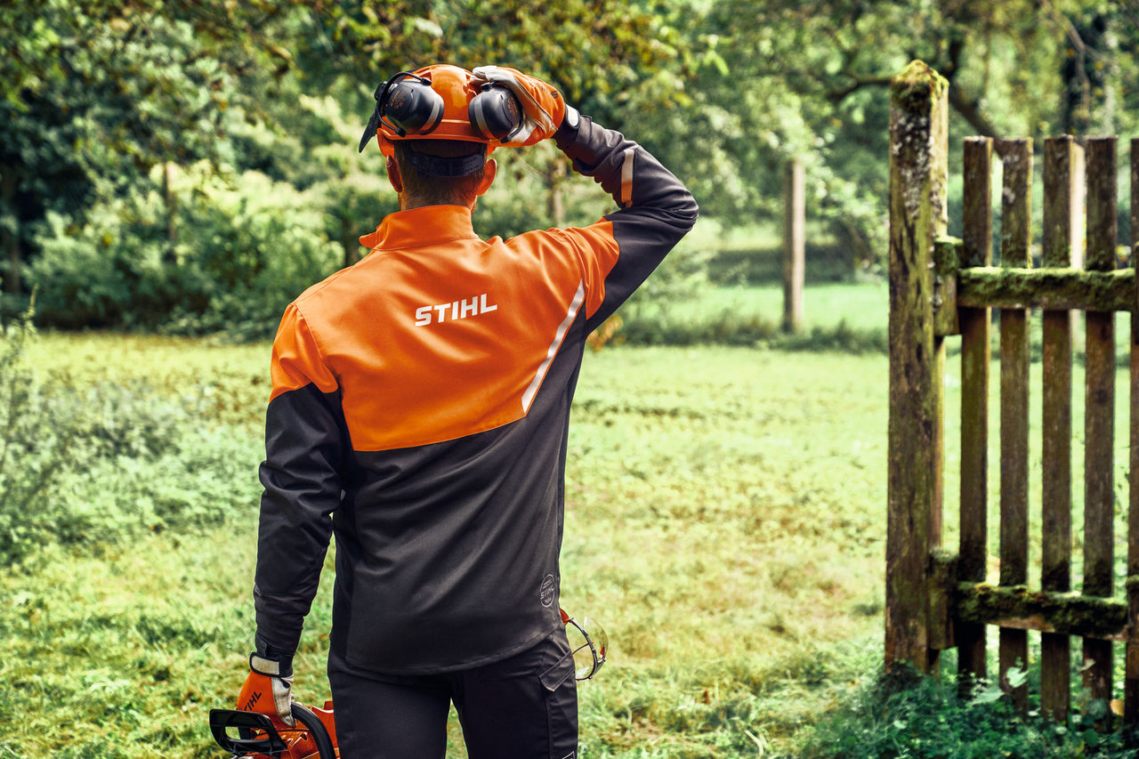Back of a man in the STIHL Function Core jacket with head and ear protection