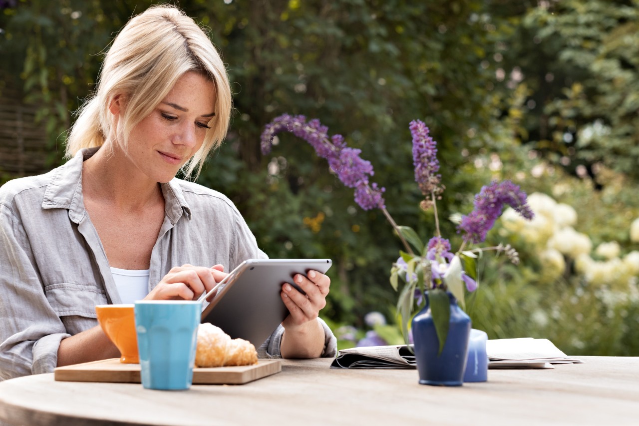 A woman using a tablet while sitting at a table outside