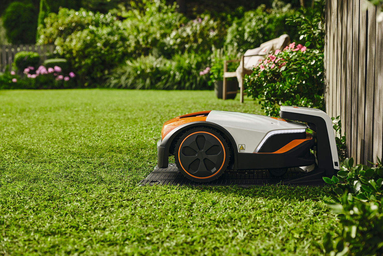 A STIHL iMOW® RMI 632 robot mower in its charging station in a garden.